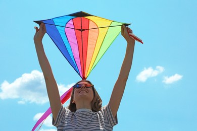Photo of Woman with colorful kite under blue sky, low angle view