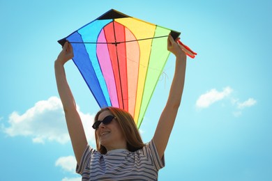 Photo of Woman with colorful kite under blue sky, low angle view