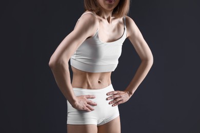Photo of Woman suffering from anorexia on grey background, closeup
