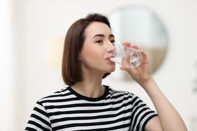 Photo of Young woman drinking water from at home