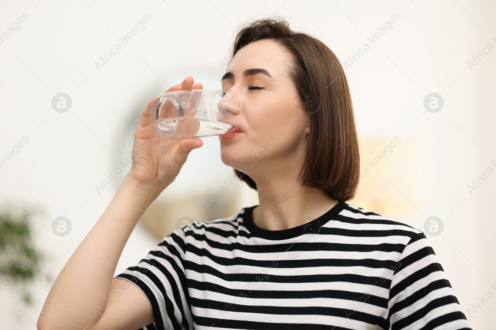 Photo of Young woman drinking water from at home