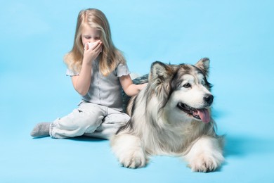 Photo of Girl suffering from allergy with her dog on light blue background