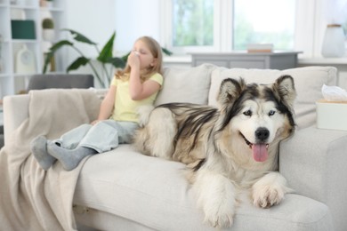 Photo of Girl suffering from allergy with her dog at home, selective focus