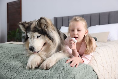 Photo of Girl suffering from allergy with her dog on bed at home