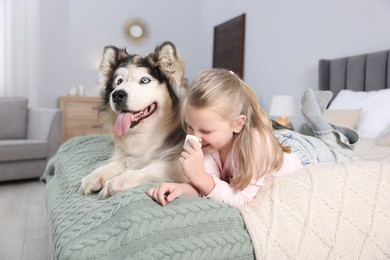 Photo of Girl suffering from allergy with her dog on bed at home