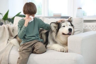 Photo of Boy suffering from allergy with her dog on sofa at home