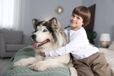 Photo of Happy boy and cute dog on bed at home