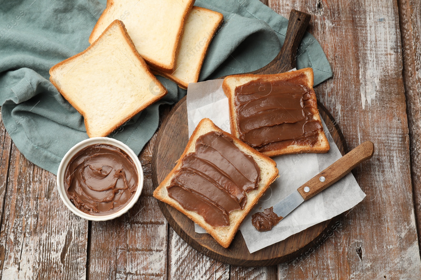 Sandwiches with chocolate butter and knife on wooden table, flat lay Photo of Sandwiches with chocolate butter and knife on wooden table, flat lay