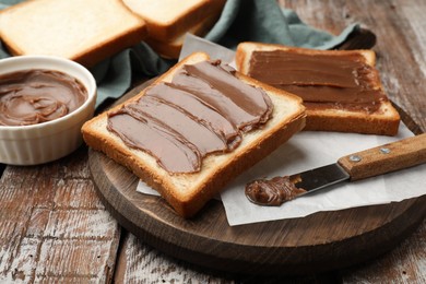 Photo of Sandwiches with chocolate butter and knife on wooden table, closeup