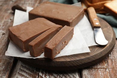 Photo of Tasty chocolate butter and knife on wooden table, closeup