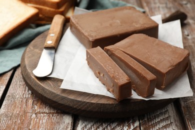 Photo of Tasty chocolate butter and knife on wooden table, closeup