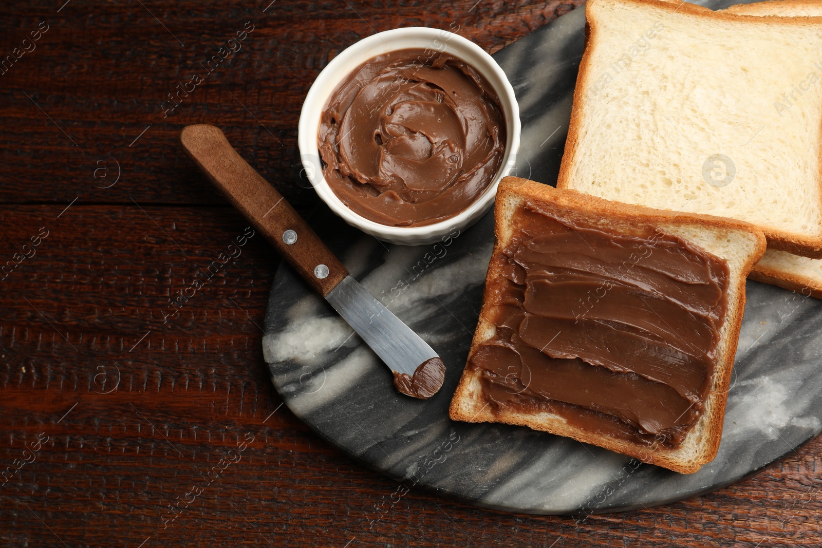 Sandwiches with chocolate butter and knife on wooden table, flat lay Photo of Sandwiches with chocolate butter and knife on wooden table, flat lay