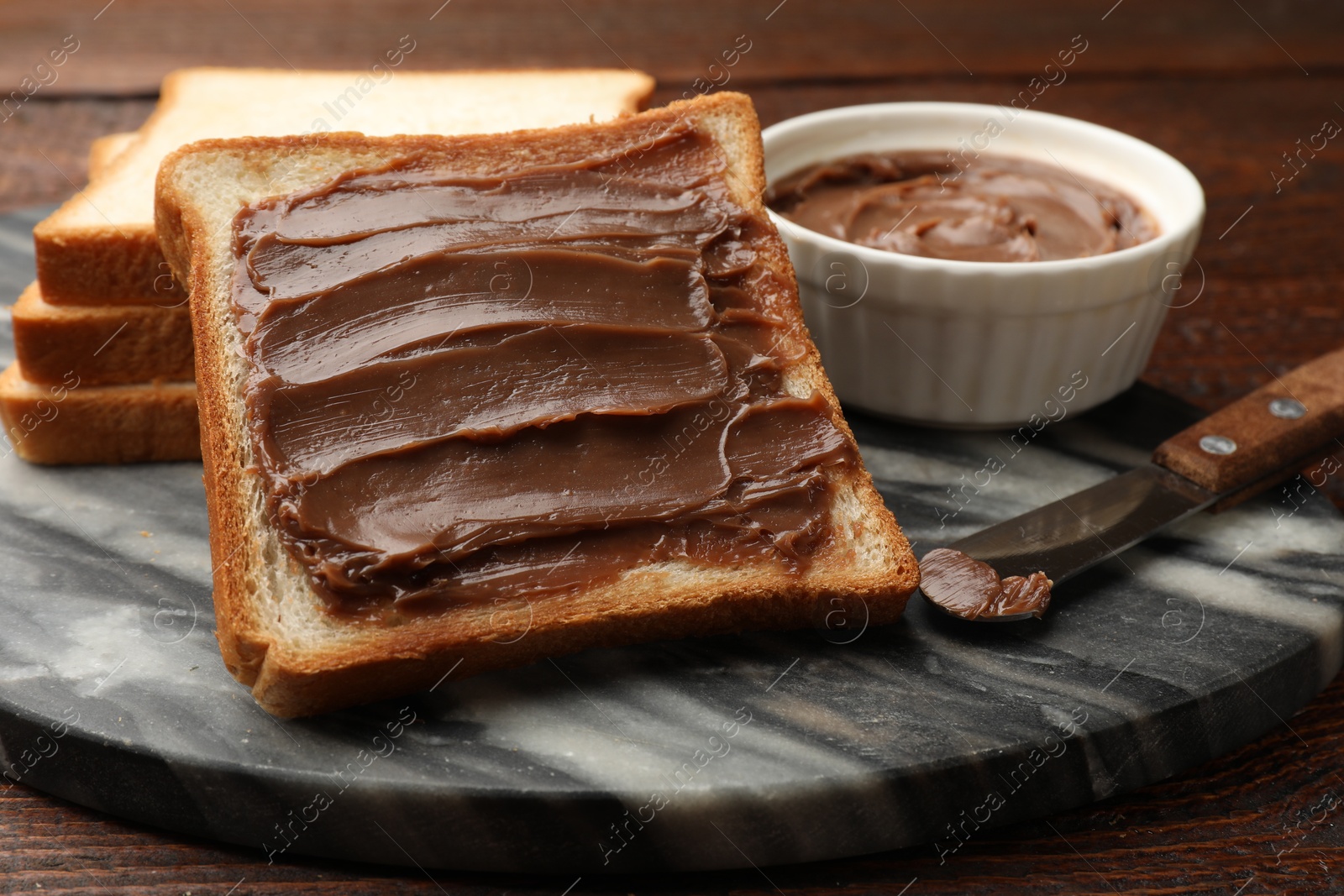 Sandwiches with chocolate butter and knife on wooden table, closeup Photo of Sandwiches with chocolate butter and knife on wooden table, closeup