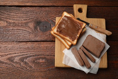 Photo of Sandwiches with chocolate butter and knife on wooden table, top view. Space for text