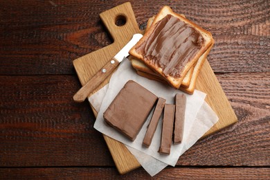 Photo of Sandwiches with chocolate butter and knife on wooden table, top view