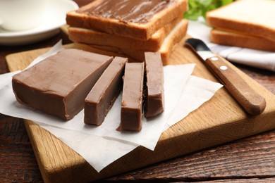 Photo of Sandwiches with chocolate butter and knife on wooden table, closeup