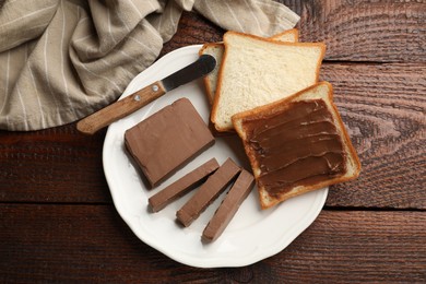 Photo of Sandwiches with chocolate butter and knife on wooden table, top view