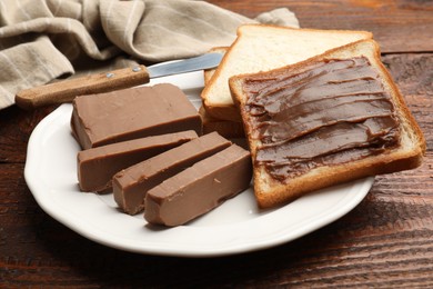 Photo of Sandwiches with chocolate butter and knife on wooden table, closeup