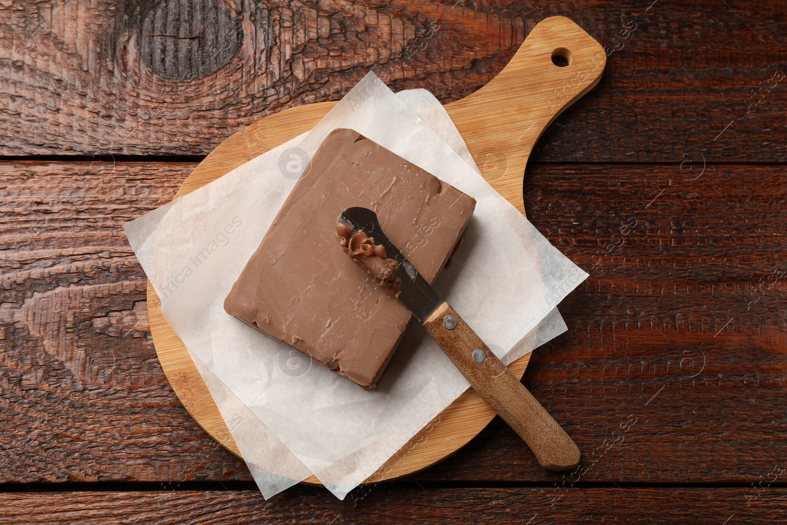 Block of tasty chocolate butter and knife on wooden table, top view Photo of Block of tasty chocolate butter and knife on wooden table, top view