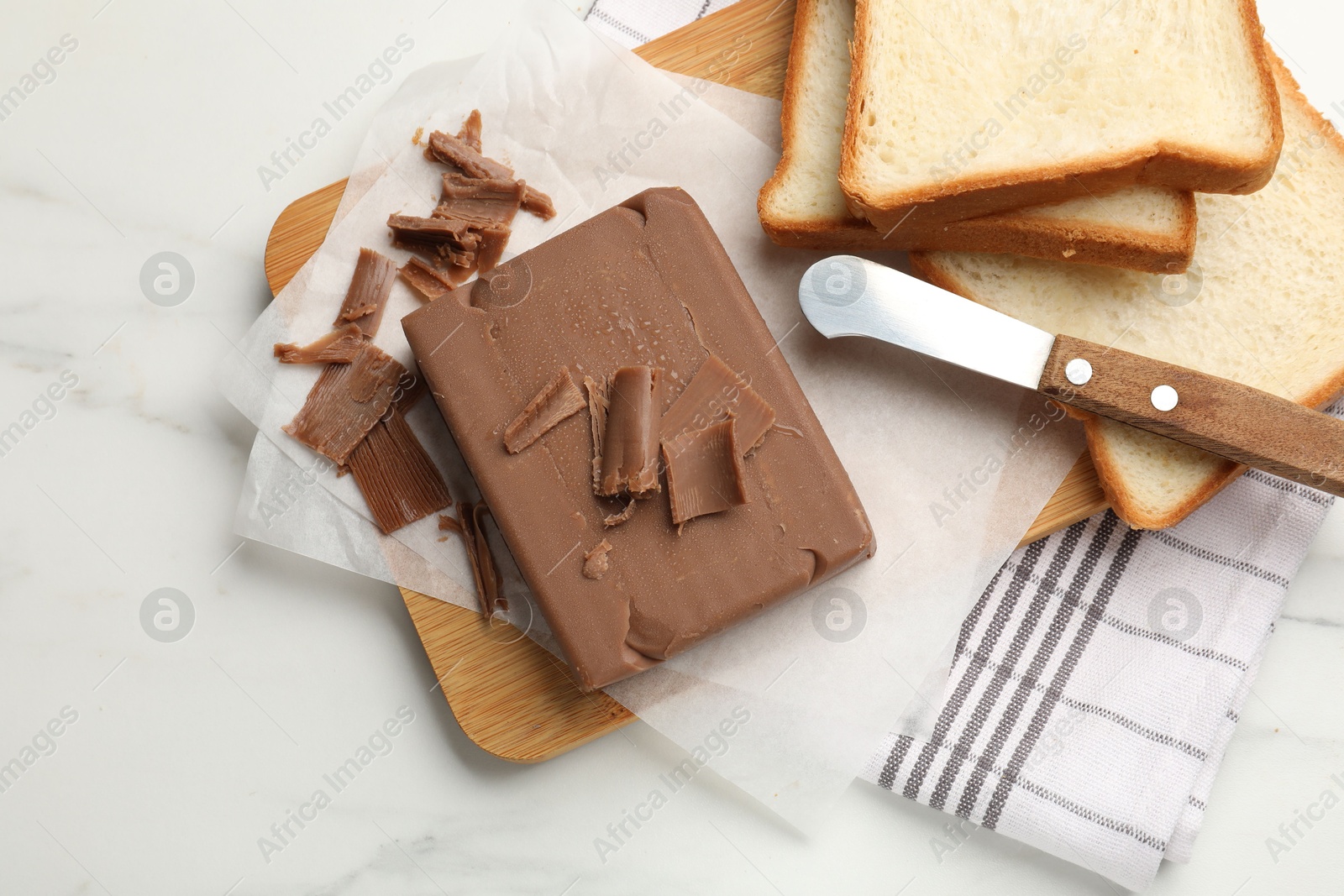 Block of tasty chocolate butter, bread slices and knife on white marble table, top view Photo of Block of tasty chocolate butter, bread slices and knife on white marble table, top view