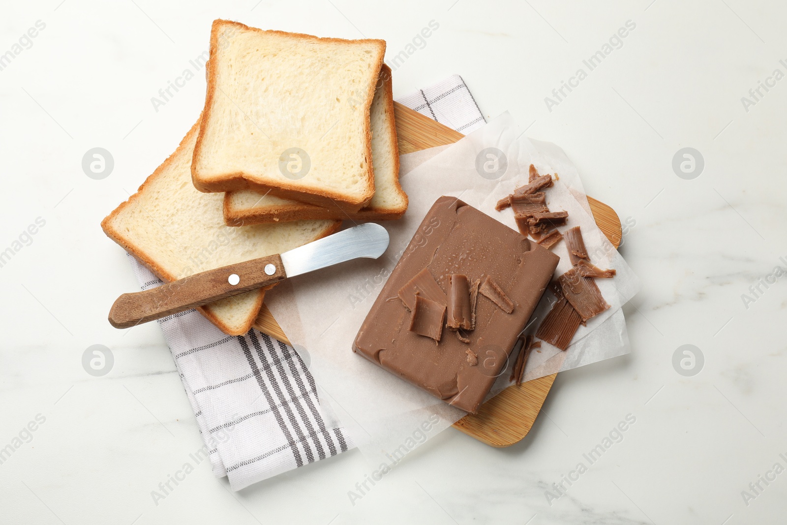 Block of tasty chocolate butter, bread slices and knife on white marble table, top view Photo of Block of tasty chocolate butter, bread slices and knife on white marble table, top view