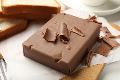 Photo of Block of tasty chocolate butter and bread slices on table, closeup