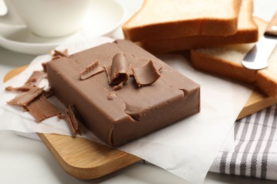 Photo of Block of tasty chocolate butter and bread slices on table, closeup