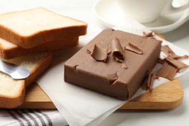 Photo of Block of tasty chocolate butter and bread slices on table, closeup