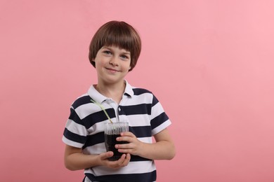 Photo of Cute little boy with glass of refreshing soda drink on pink background