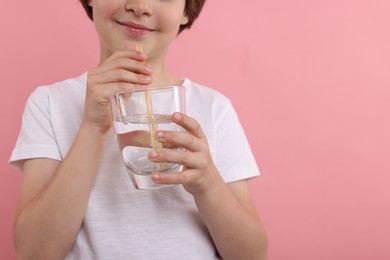 Photo of Little boy with glass of refreshing soda drink on pink background, closeup. Space for text