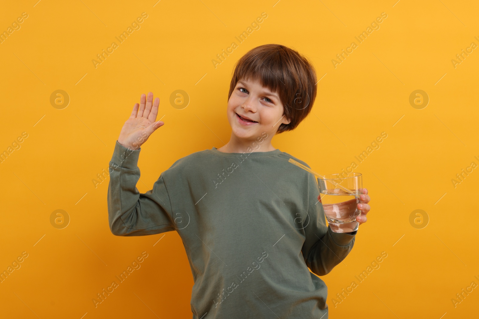 Cute little boy with glass of refreshing soda drink on orange background Photo of Cute little boy with glass of refreshing soda drink on orange background