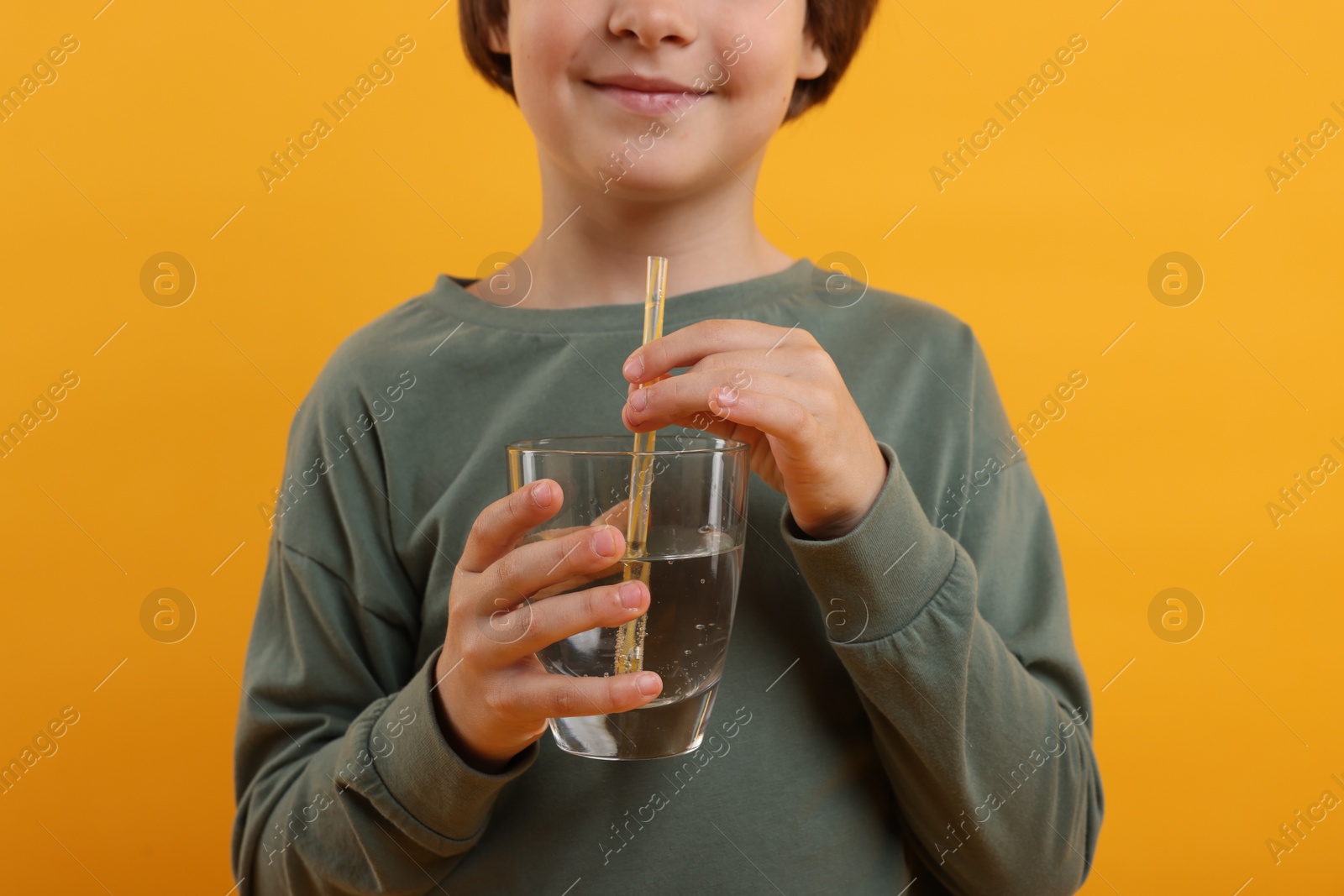 Little boy with glass of refreshing soda drink on orange background, closeup Photo of Little boy with glass of refreshing soda drink on orange background, closeup
