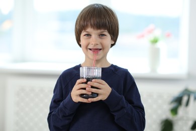 Photo of Happy little boy drinking refreshing soda at home
