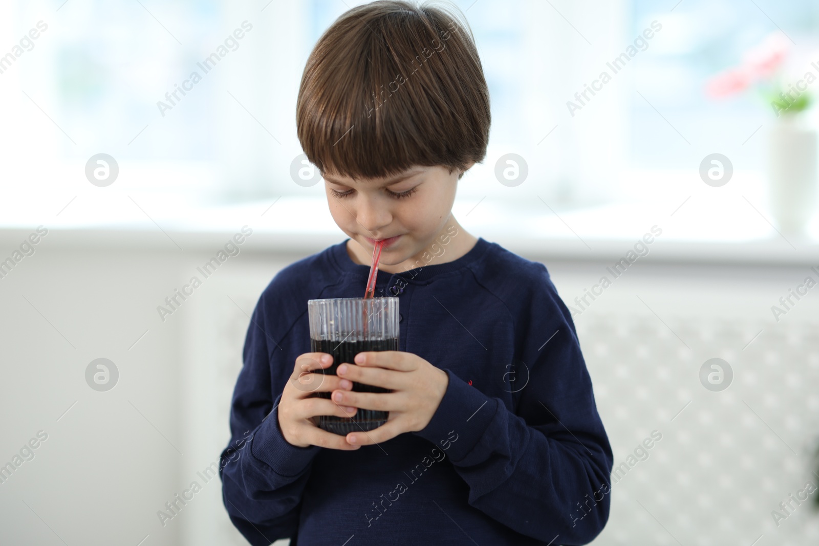 Photo of Cute little boy drinking refreshing soda at home