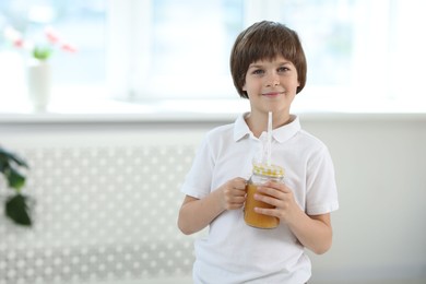 Photo of Cute little boy with mason jar of orange juice at home, space for text. Refreshing drink