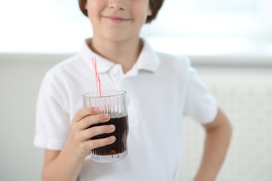 Photo of Little boy with glass of refreshing soda at home, selective focus