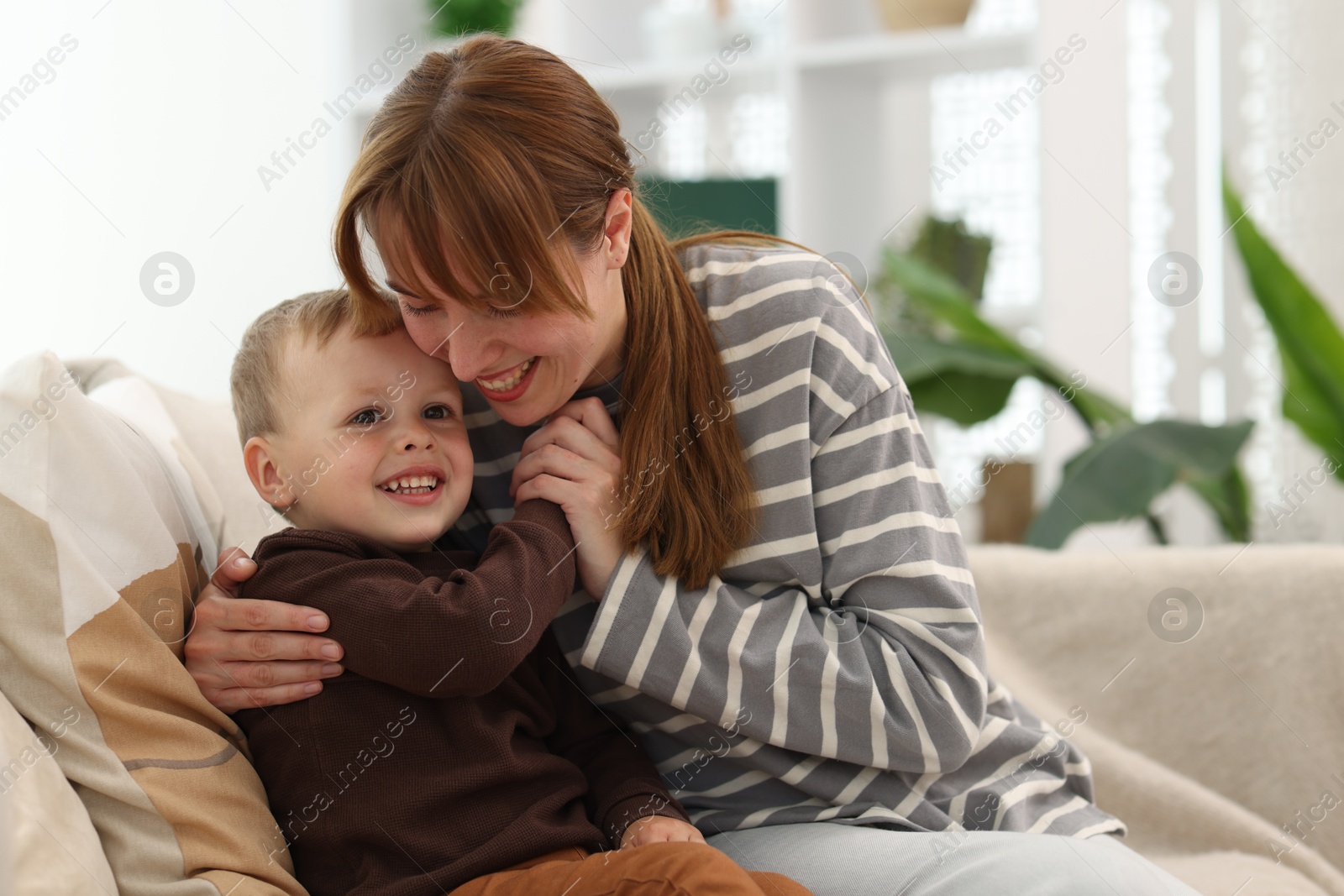 Happy mother spending time together with her son on sofa at home Photo of Happy mother spending time together with her son on sofa at home