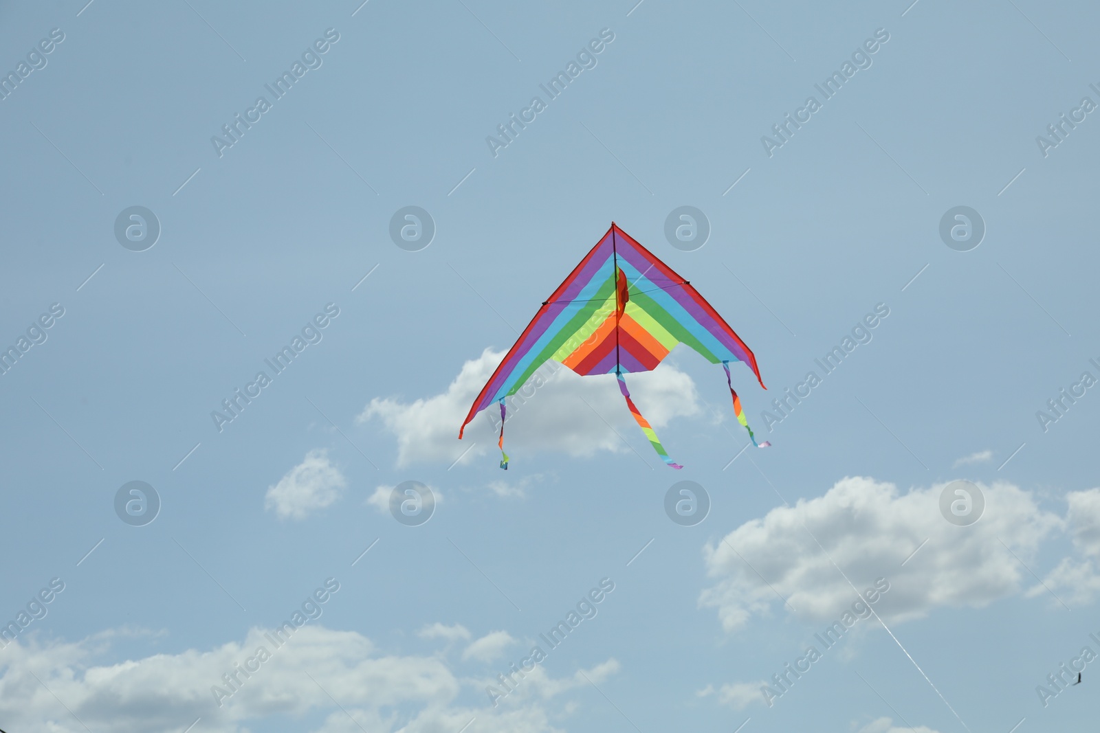 Colorful kite flying in blue sky, low angle view Photo of Colorful kite flying in blue sky, low angle view