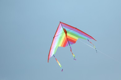 Photo of Colorful kite flying in blue sky, bottom view. Space for text