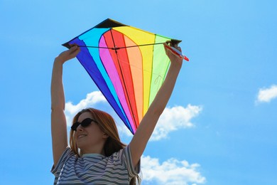 Photo of Woman with colorful kite under blue sky, low angle view