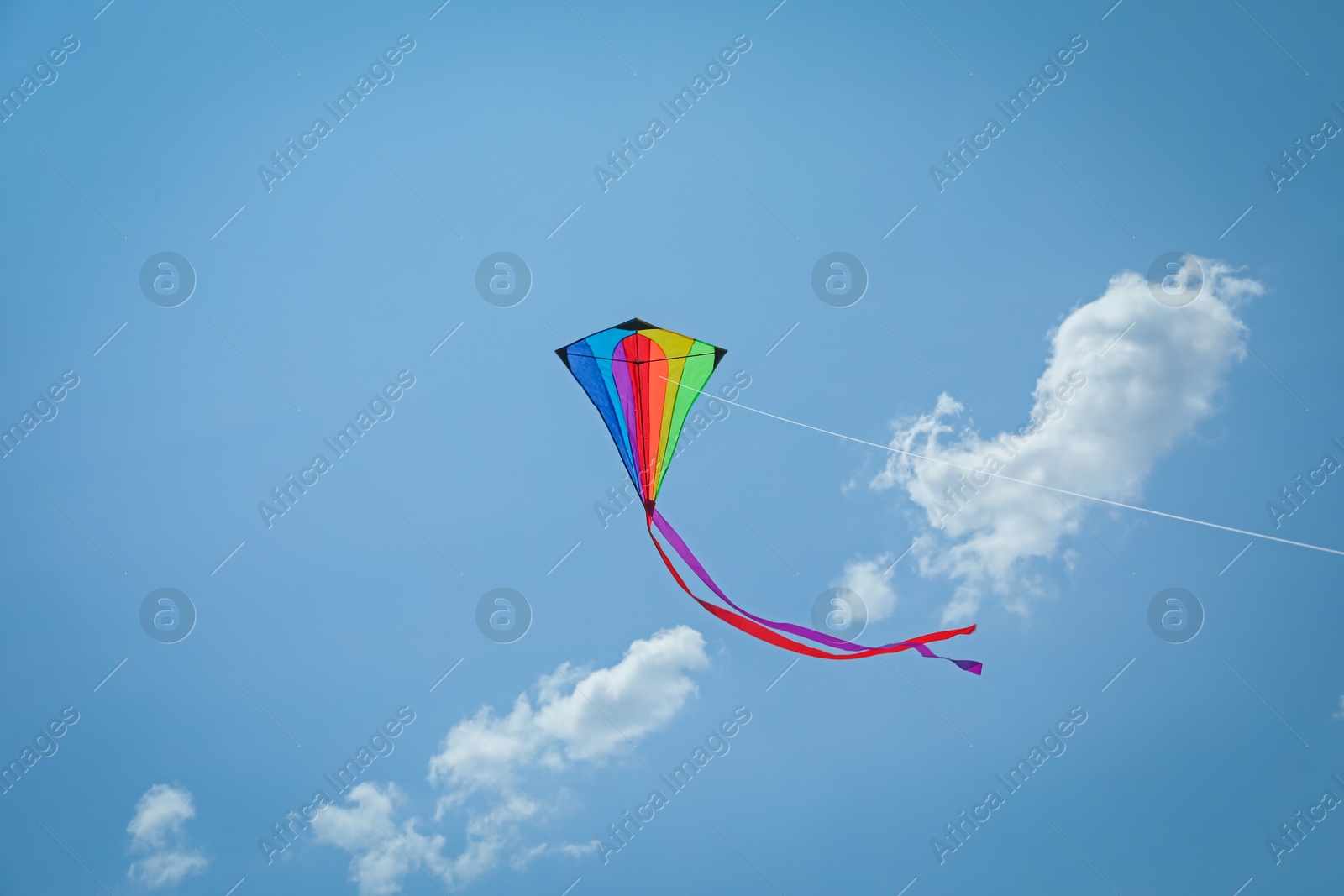 Colorful kite flying in blue sky, low angle view Photo of Colorful kite flying in blue sky, low angle view