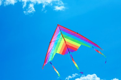Photo of Colorful kite flying in blue sky, bottom view. Space for text