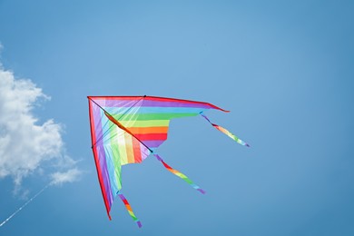 Photo of Colorful kite flying in blue sky, low angle view. Space for text