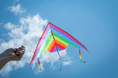 Photo of Woman with colorful kite under blue sky, bottom view