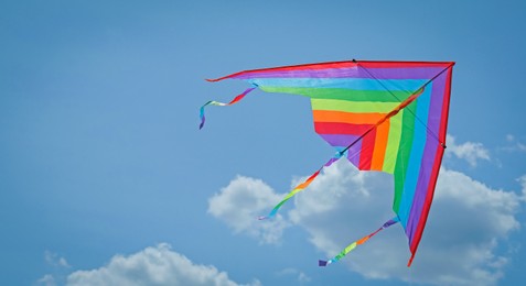 Photo of Colorful kite flying in blue sky, bottom view. Space for text