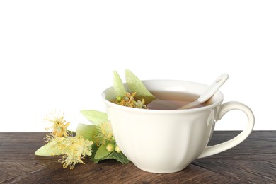 Photo of Tasty linden tea in cup, leaves and flowers on wooden table against white background