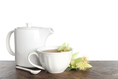 Photo of Tasty linden tea in cup, teapot, leaves and flowers on wooden table against white background