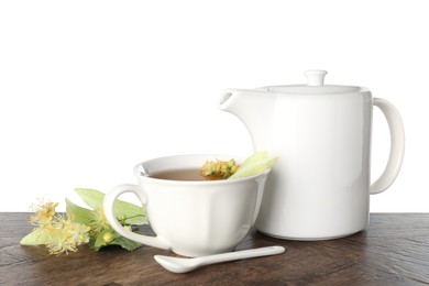 Photo of Tasty linden tea in cup, teapot, leaves and flowers on wooden table against white background