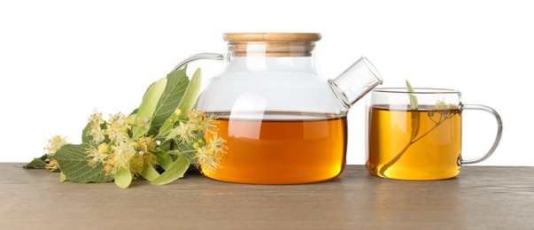 Photo of Tasty linden tea in cup, teapot, leaves and flowers on wooden table against white background