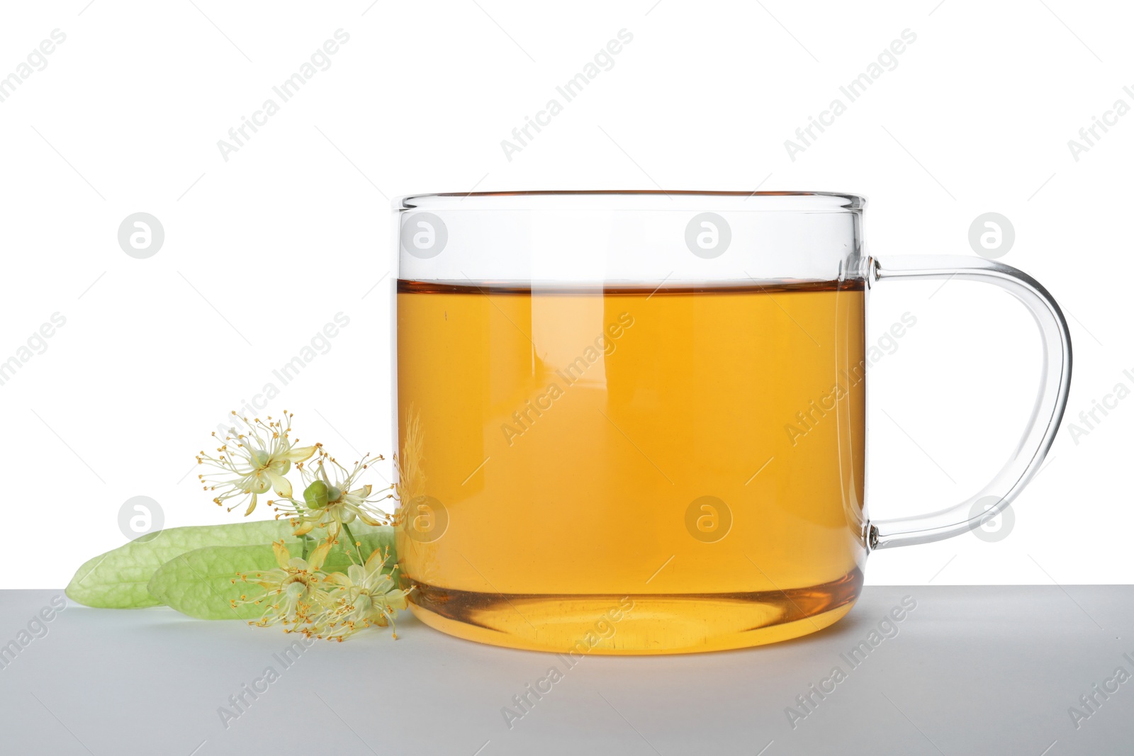 Tasty linden tea in cup, leaves and flowers isolated on white Photo of Tasty linden tea in cup, leaves and flowers isolated on white